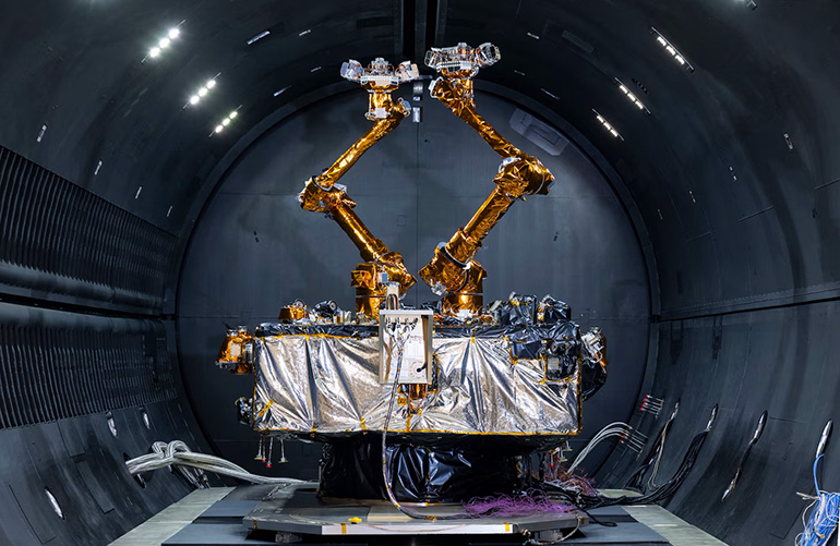 The Robotic Servicing of Geosynchronous Satellites (RSGS) payload, two gold robotic arms inside a grey tunnel.