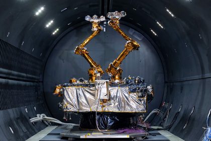 The Robotic Servicing of Geosynchronous Satellites (RSGS) payload, two gold robotic arms inside a grey tunnel.