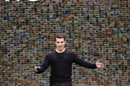 Man in black shirt stands in front of screen displaying thousands of small images