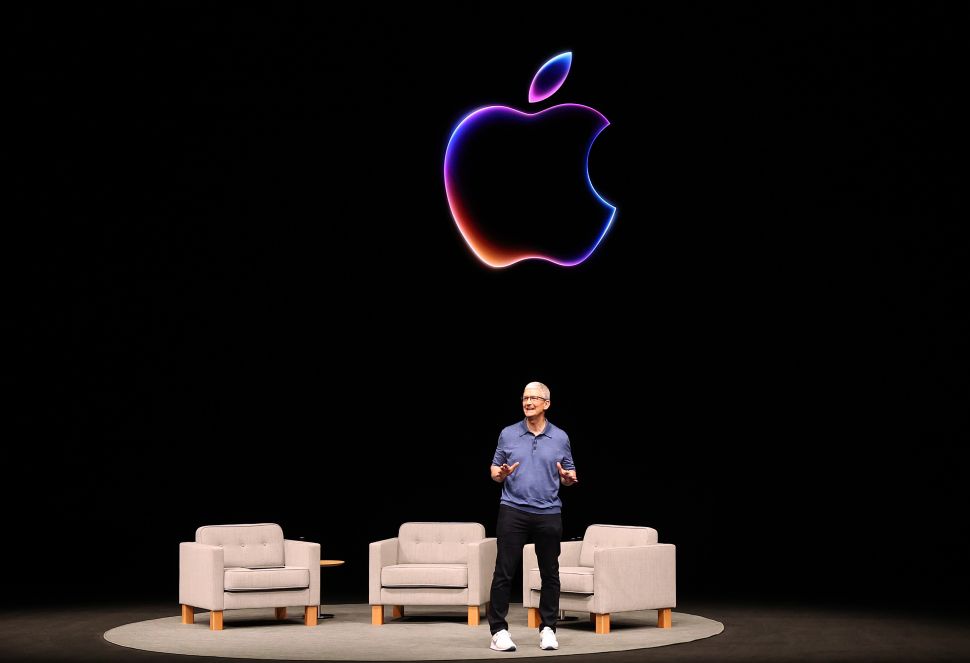 Man stands on stage behind black screen with outline of Apple logo