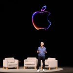 Man stands on stage behind black screen with outline of Apple logo