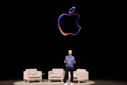 Man stands on stage behind black screen with outline of Apple logo