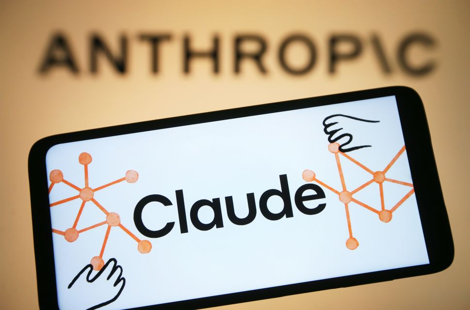 Mobile phone with words 'Claude' on it displayed in front of orange background with word 'Anthropic.'