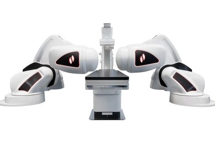 The Stereotaxis Genesis RMN, which features two large, white robotic arms with magnets on each end, sitting in between the arms is a table.