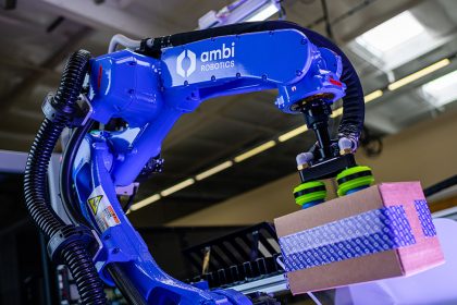 Ambi Robotics 的 AmbiSort A 系列机器人正在抓取一个带有紫色灯光的纸板箱。