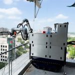 Raise Robotics 系统展示了两个 UR20 协作机器人，它们在建筑物的边缘工作。