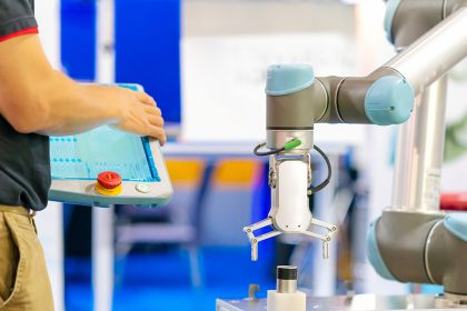 A cobot arm about to pick up an item next to a person holding a tablet. Collaborative robot sales should rebound, according to ABI Research.