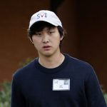 一位戴白色帽子的亚洲男子穿着黑色T恤。