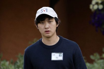 一位戴白色帽子的亚洲男子穿着黑色T恤。