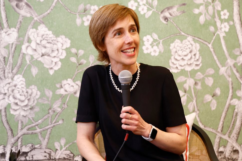 一位女士坐在椅子上，对着麦克风讲话