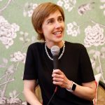 一位女士坐在椅子上，对着麦克风讲话